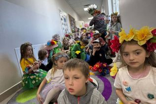 Grupa przedszkolaków w strojach wiosennych podczas wiosennego pokazu mody.