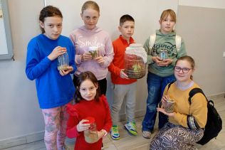 Uczniowie trzymający słoje z patyczakami
